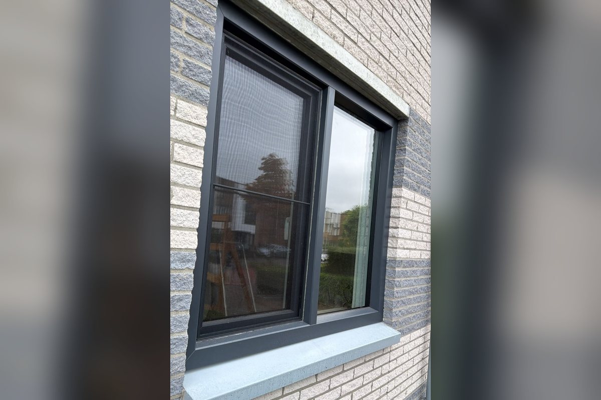Antraciet kunststof kozijn met draairaam in een lichte bakstenen gevel