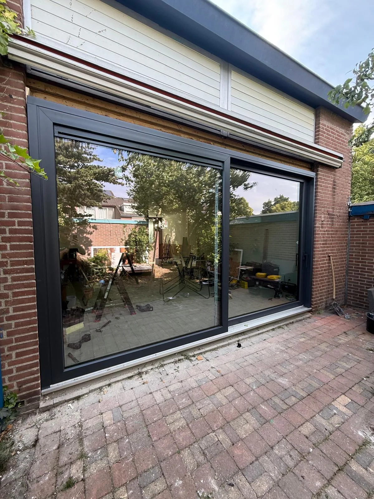 Antraciet kozijn met groot raam in een aanbouw