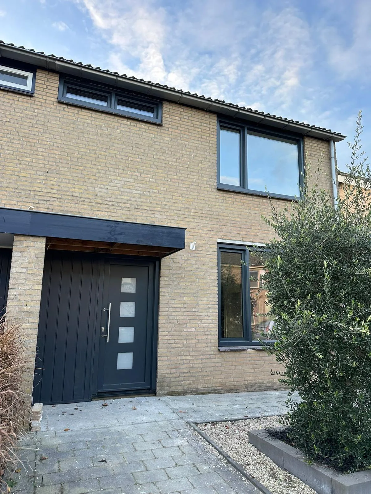 Antraciet voordeur met glasstroken in een rijwoning